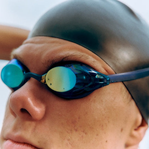 Person wearing swim goggles and cap with a blurred background