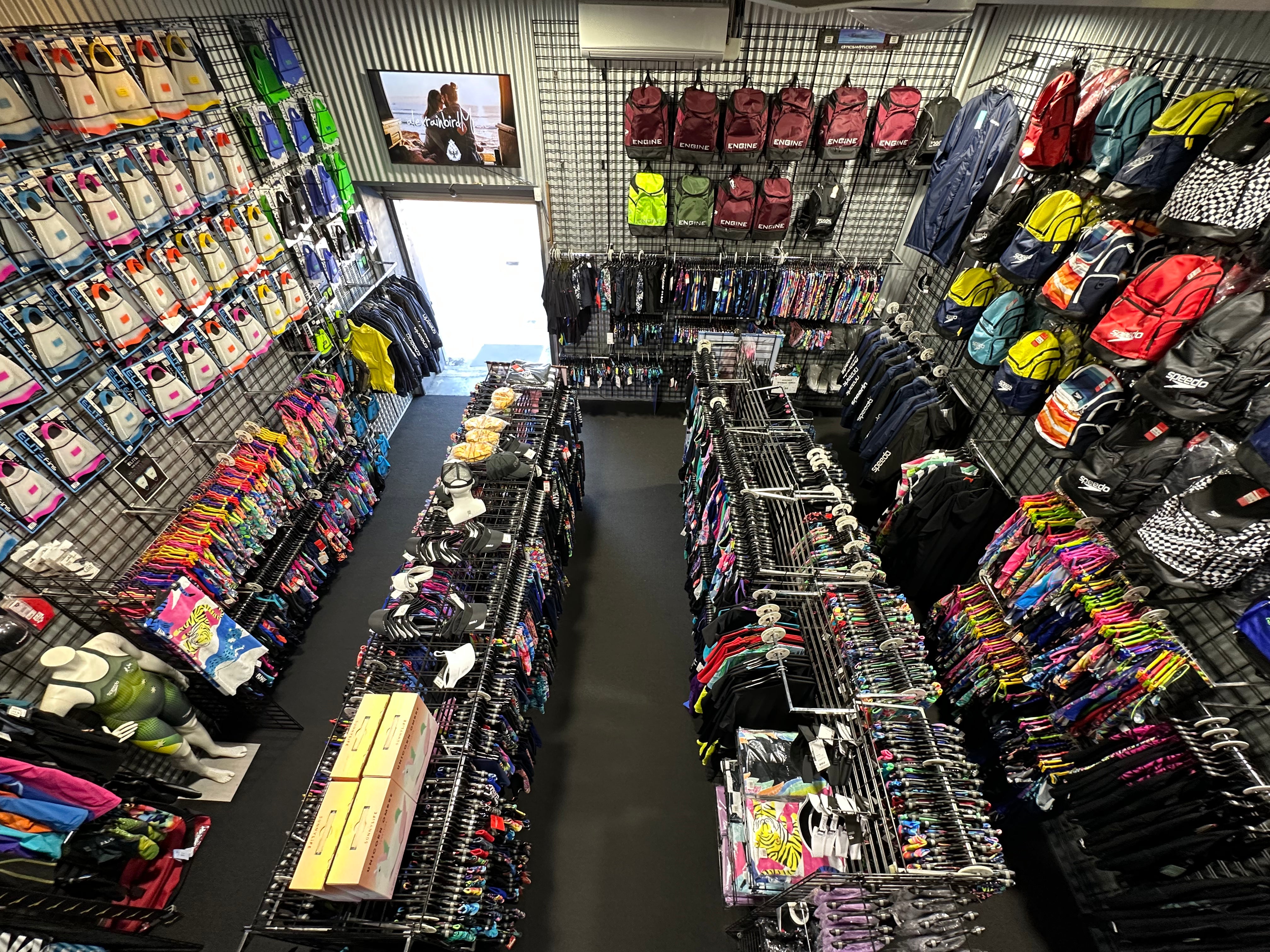 Store interior with shelves stocked with colorful bags and backpacks.