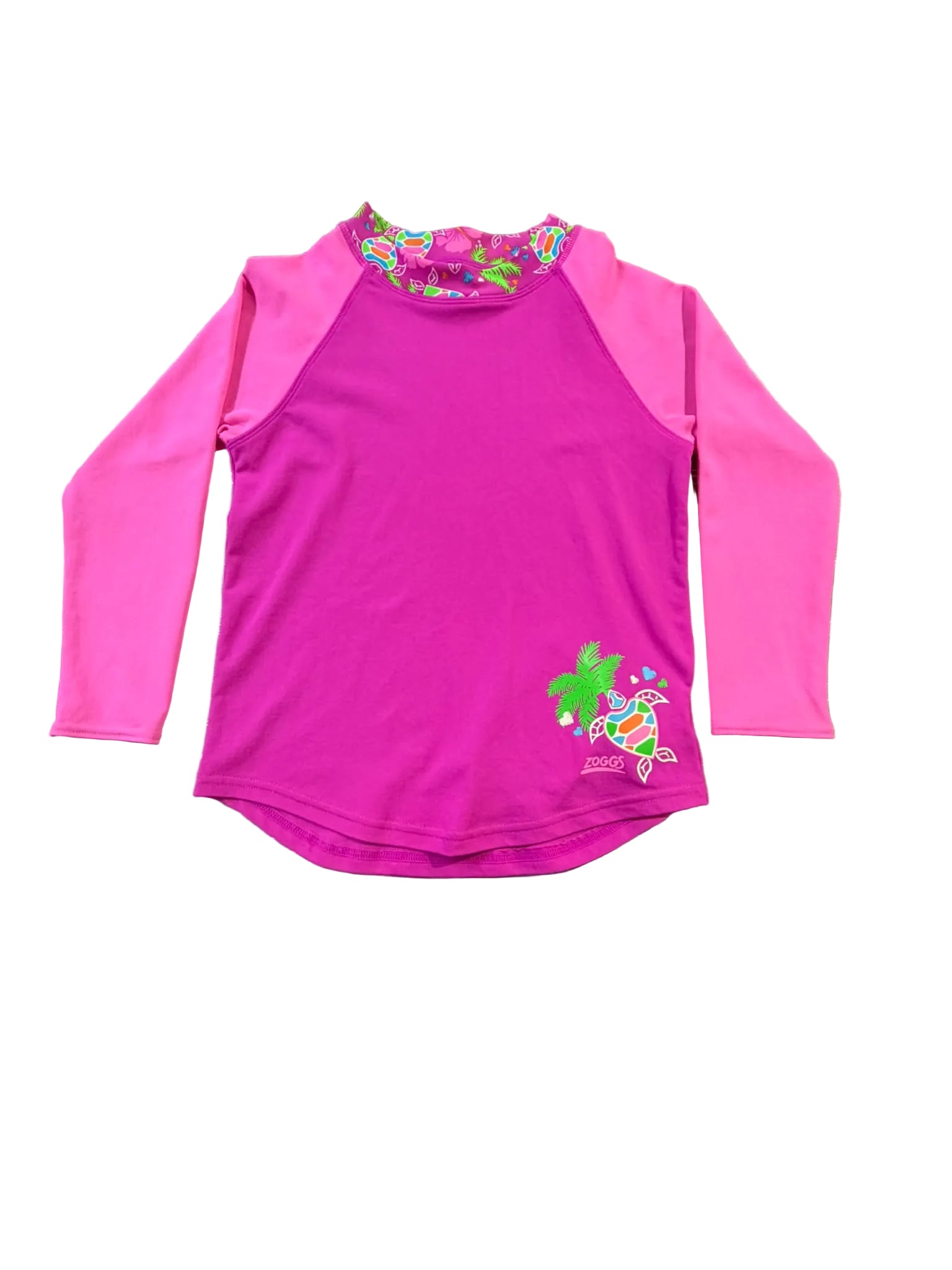 A pink long-sleeve rash guard swimsuit with a colorful floral pattern around the collar and a turtle graphic on the lower right, laid flat on a wooden table.