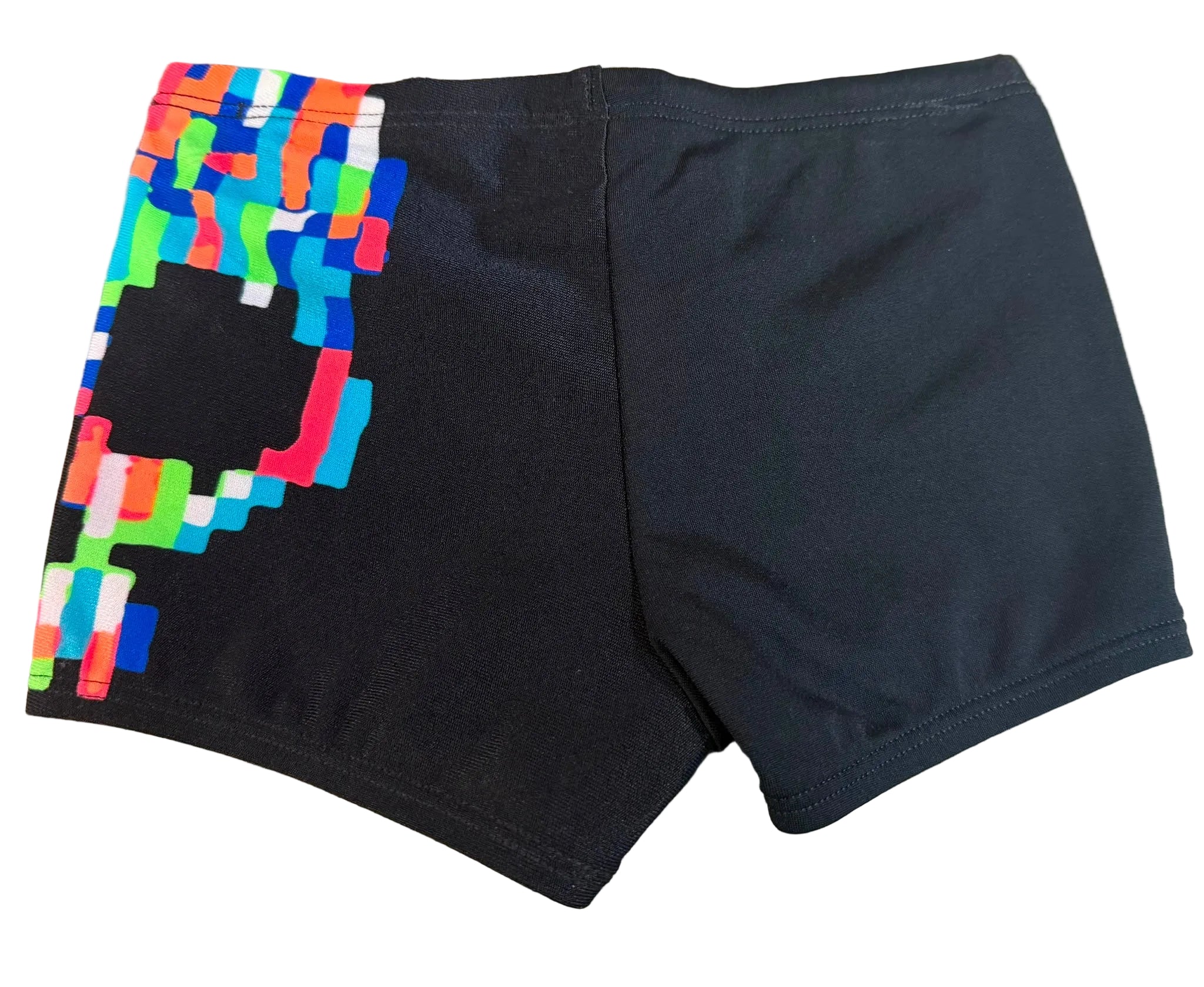 Black athletic shorts with a colorful pixelated graphic on the left leg, laid flat on a wood-grain surface.